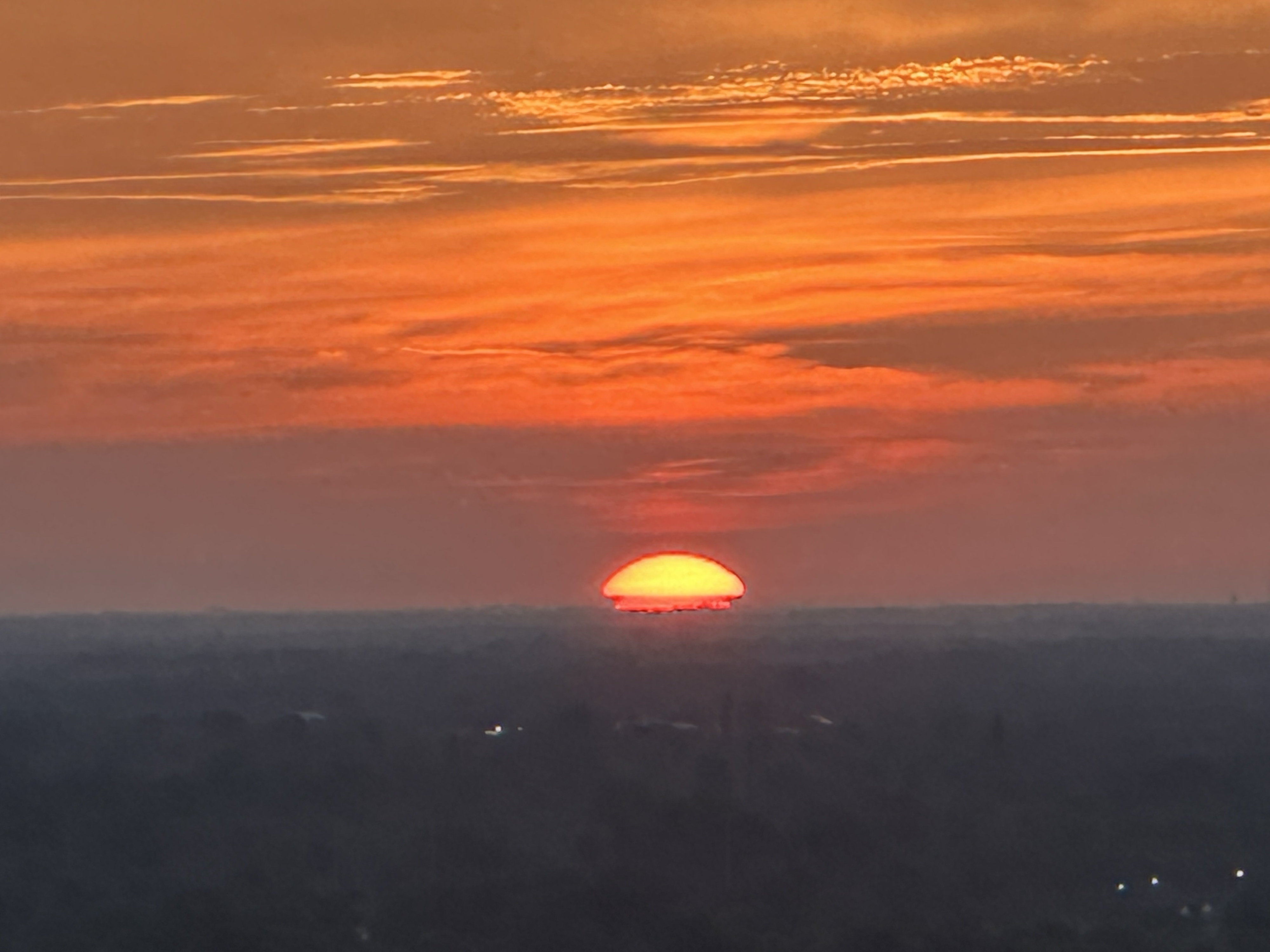 Landscape in shadow as sun rises. An optical illusion happens where the sun looks to turn into a hard shell with tiny legs underneath. Like a bug. Like Gregor. No edits iPhone.